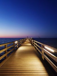 Pier over sea against clear blue sky