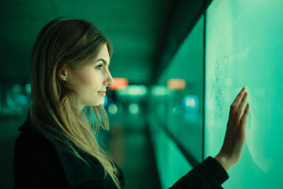 Close-up side view of young woman against green wall