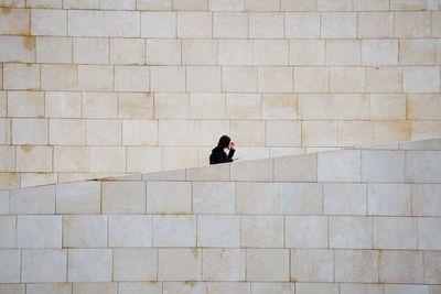 Full length of woman walking on brick wall of building