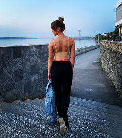 Rear view of young woman standing against the wall