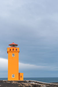 Lighthouse by sea against sky