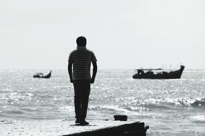 Rear view of man walking on pier at beach