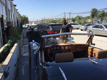 Vehicles on road against sky in city