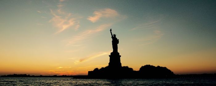 Silhouette statue of liberty against sky during sunset
