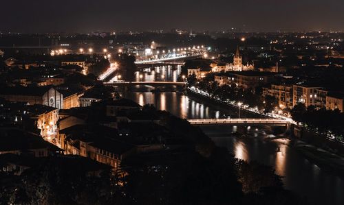 Illuminated bridge over river in city at night