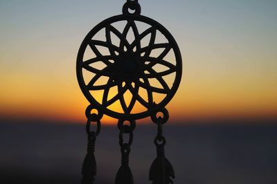 Close-up of silhouette hanging against sky during sunset