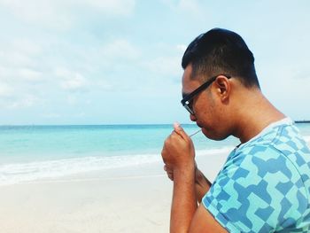 Close-up of man at beach against sky