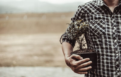 Midsection of man holding umbrella standing outdoors