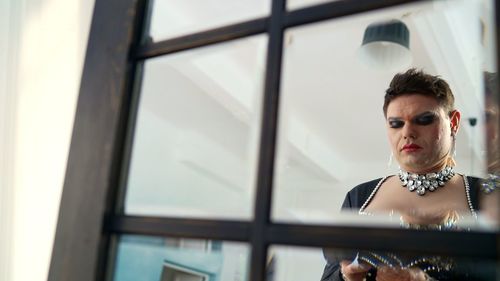 Portrait of young woman looking through window