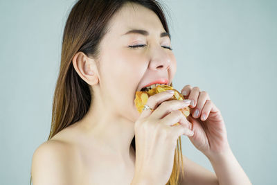 Close-up of woman eating food against white background