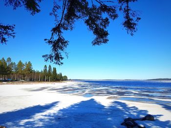 Scenic view of snow covered land against clear blue sky