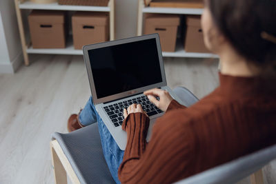 Rear view of woman using laptop at home