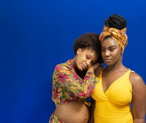 Portrait of two women against blue background. 