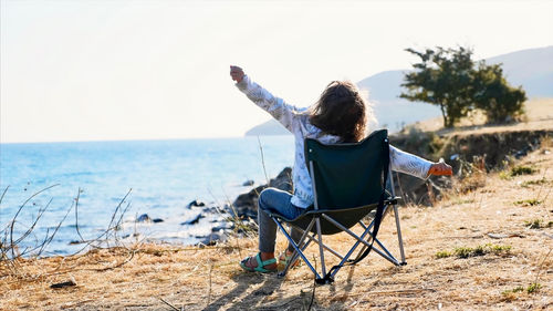 Rear view of woman sitting on beach