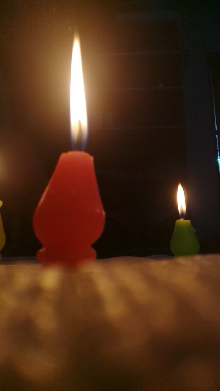 CLOSE-UP OF LIT CANDLE IN THE DARK