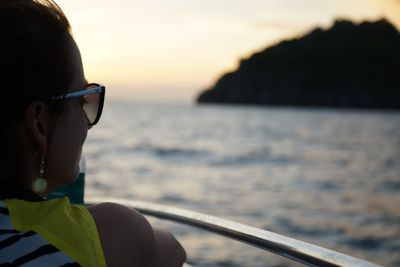 Cropped image of woman on boat in sea during sunset