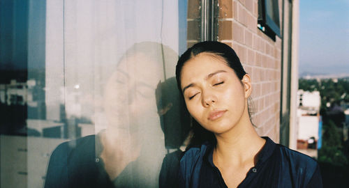 Portrait of young woman looking through window