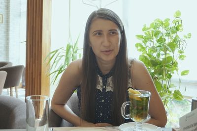 Young woman having drink at table in restaurant