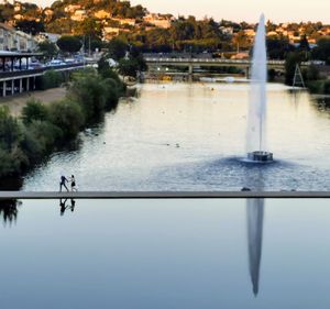 Scenic view of lake against sky in city