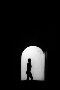 Side view of silhouette man standing against dark wall