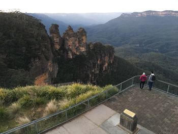 Rear view of people standing on mountain against sky