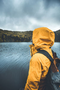 Rear view of man looking at lake against sky