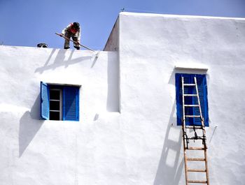 Low angle view of man standing on terrace painting house