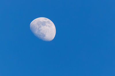 Low angle view of moon in clear blue sky