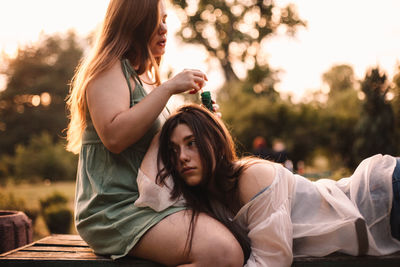 Lesbian couple playing with bubbles while relaxing in park in summer