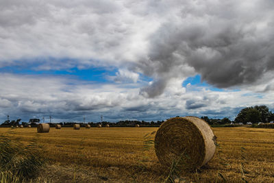 Hay bales on field against sky