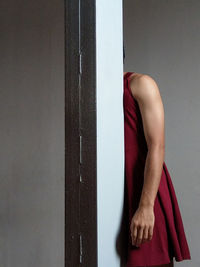 Midsection of man wearing maroon dress standing against wall