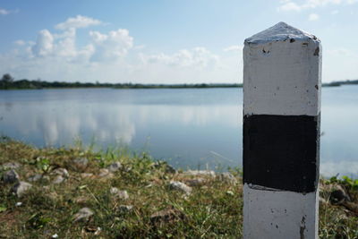 Close-up of wooden post at lakeshore against sky