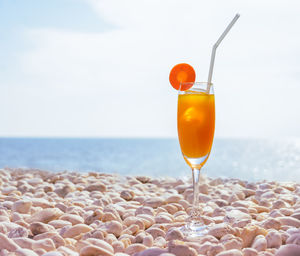 Close-up of drink by sea against sky