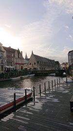 View of buildings by canal against cloudy sky