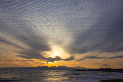 Scenic view of sea against dramatic sky during sunset