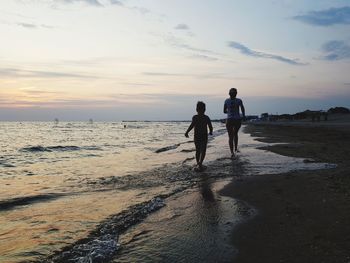 People on beach against sky during sunset