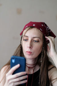 Portrait of a girl in a red bandana with a phone in her hand and long dark hair.