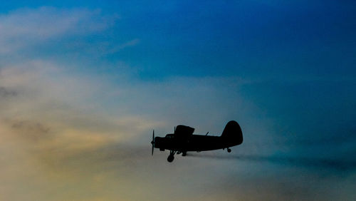 Low angle view of silhouette airplane against sky at sunset