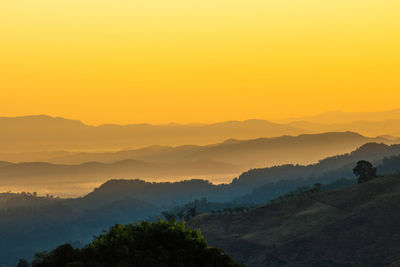 Scenic view of silhouette mountains against orange sky