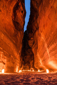 Illuminated lighting equipment on land by rock formations at night