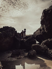 People standing on rock against sky