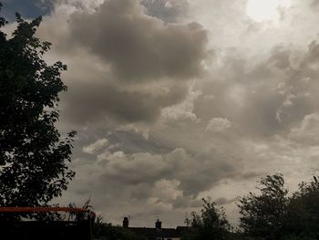 Low angle view of trees against cloudy sky