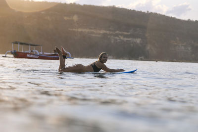 Female surfer in the ocean at sunset