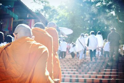 Rear view of monks and people on steps at temple