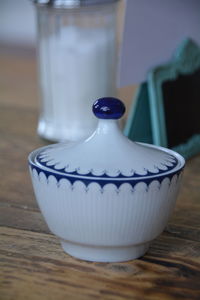 Close-up of white and blue ceramic container on wooden table
