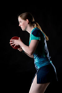 Side view of a young woman against black background