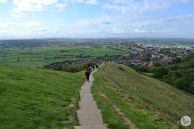 People walking on street amidst landscape against sky