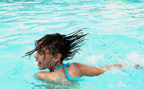 Rear view of woman laughing while swimming in pool