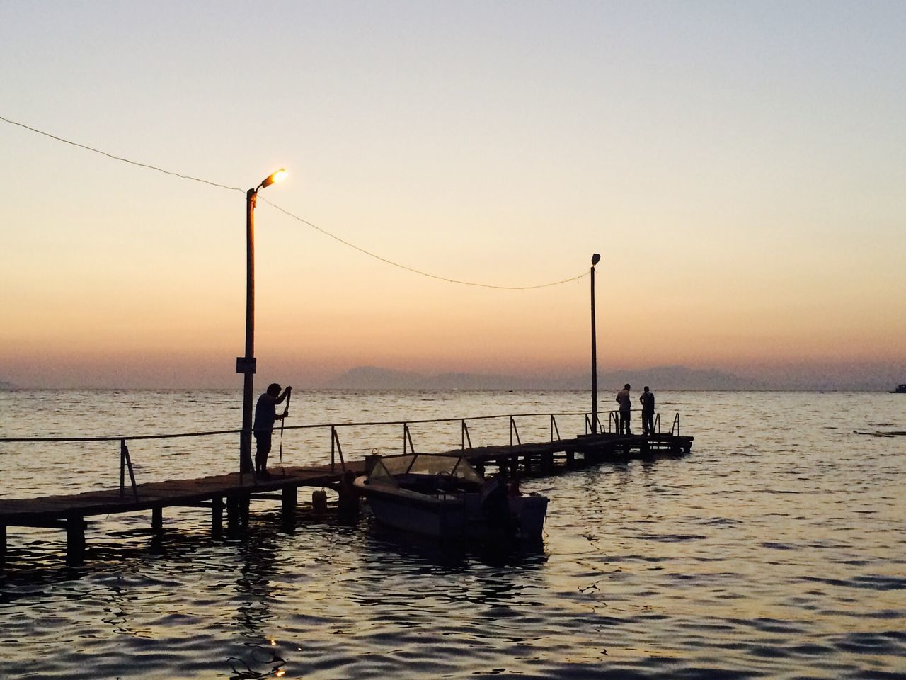 water, sea, sunset, silhouette, horizon over water, scenics, tranquility, tranquil scene, beauty in nature, clear sky, rippled, nautical vessel, nature, pier, transportation, waterfront, idyllic, boat, orange color, sky