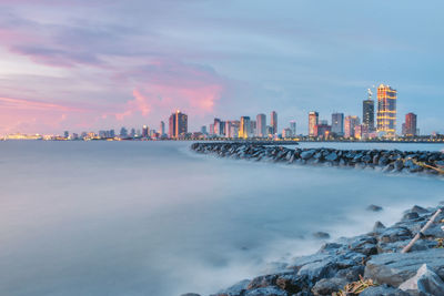 Scenic view of sea and buildings against sky during sunset